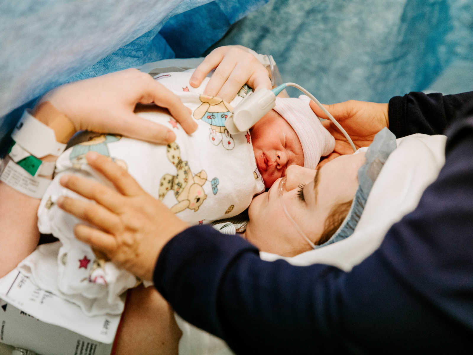 Woman who just had c-section holds new born baby swaddled in blanket close to her chest