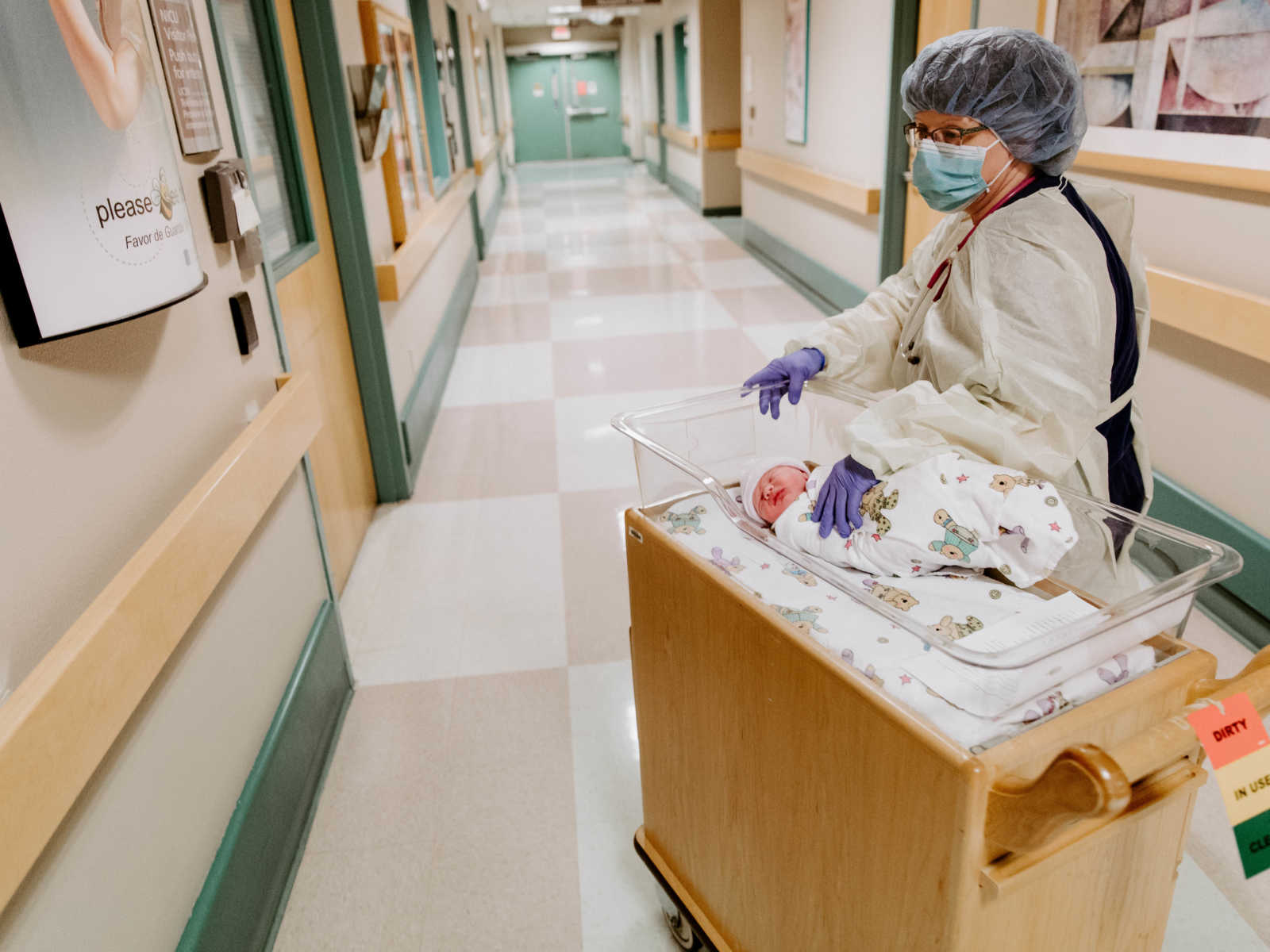 Nurse pushes baby who was born through c-section down the hospital hallway on cart with baby bed on it