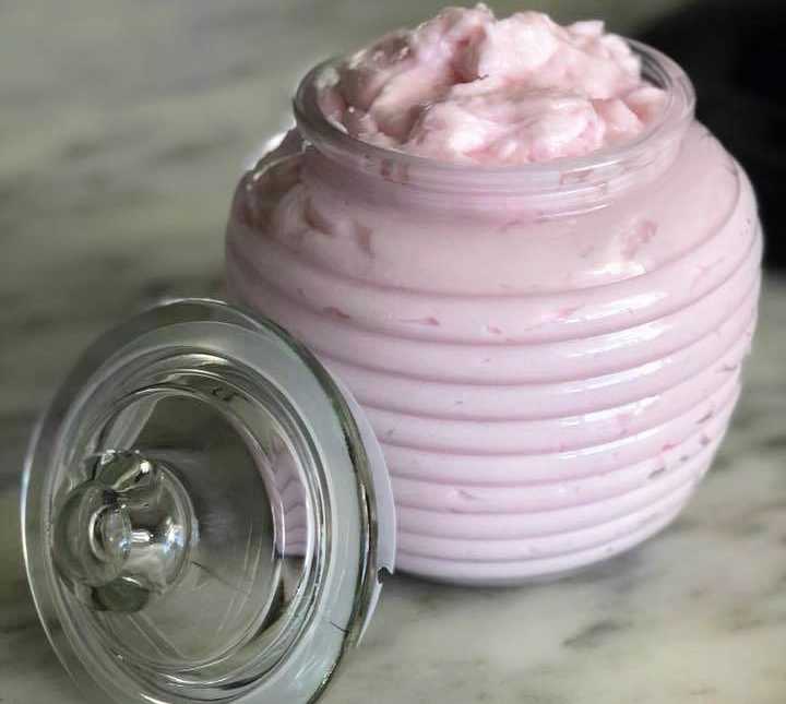 a clear opened jar with a pink substance inside with the lid balancing next to the jar
