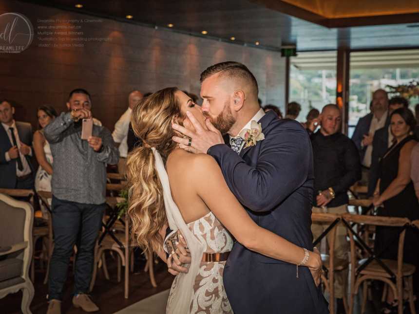 bride and deaf groom share a kiss while wedding guests look on