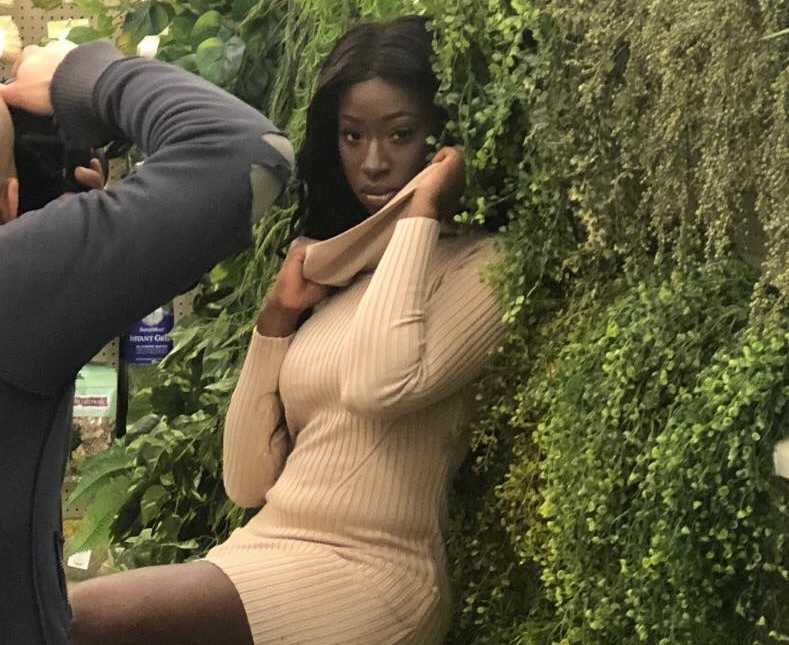 woman leaning against greenery and a photographer capturing the moment