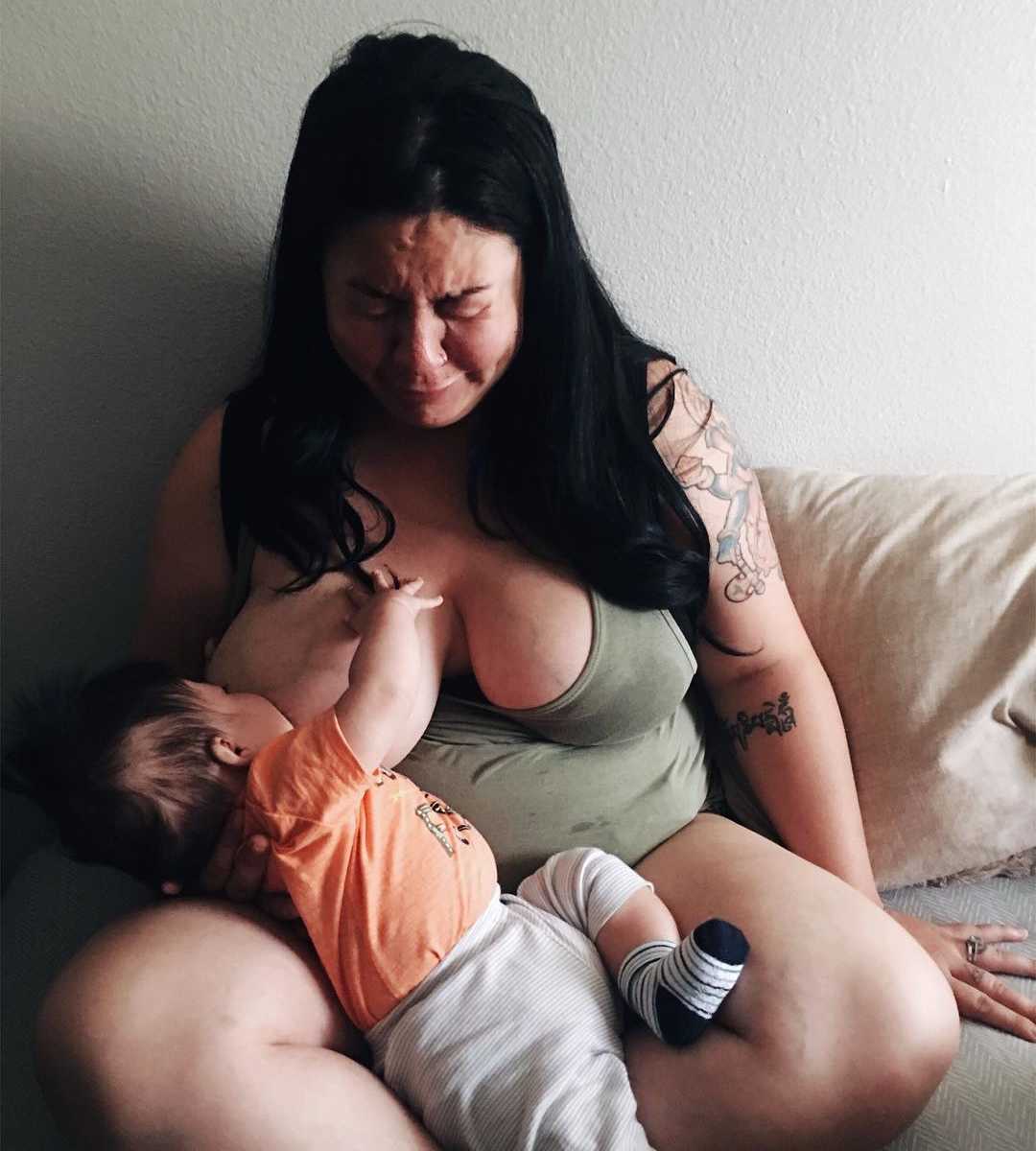 woman struggling with postpartum depression cries while breastfeeding baby