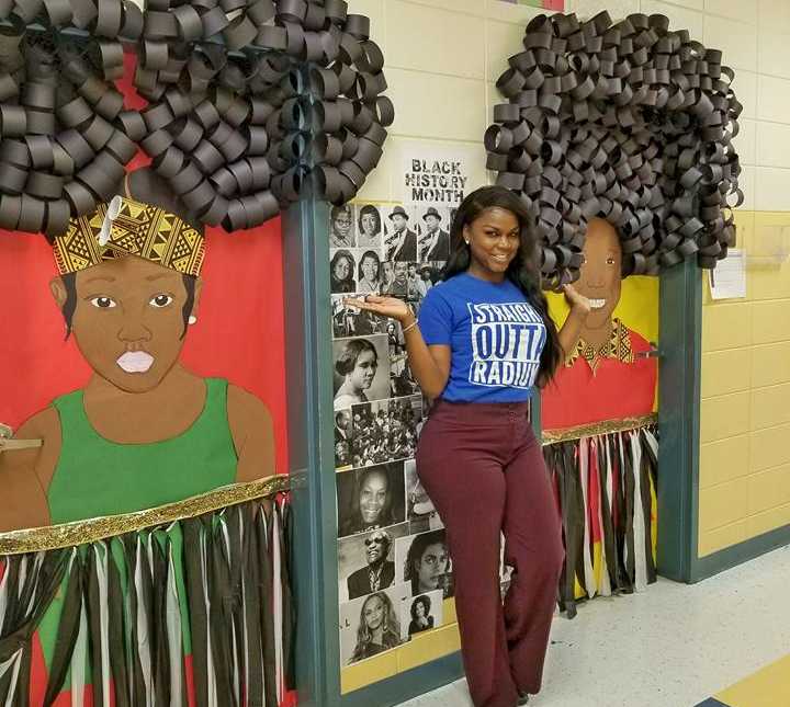 teacher stands in front of elaborate black history month decorations that cover classroom doors