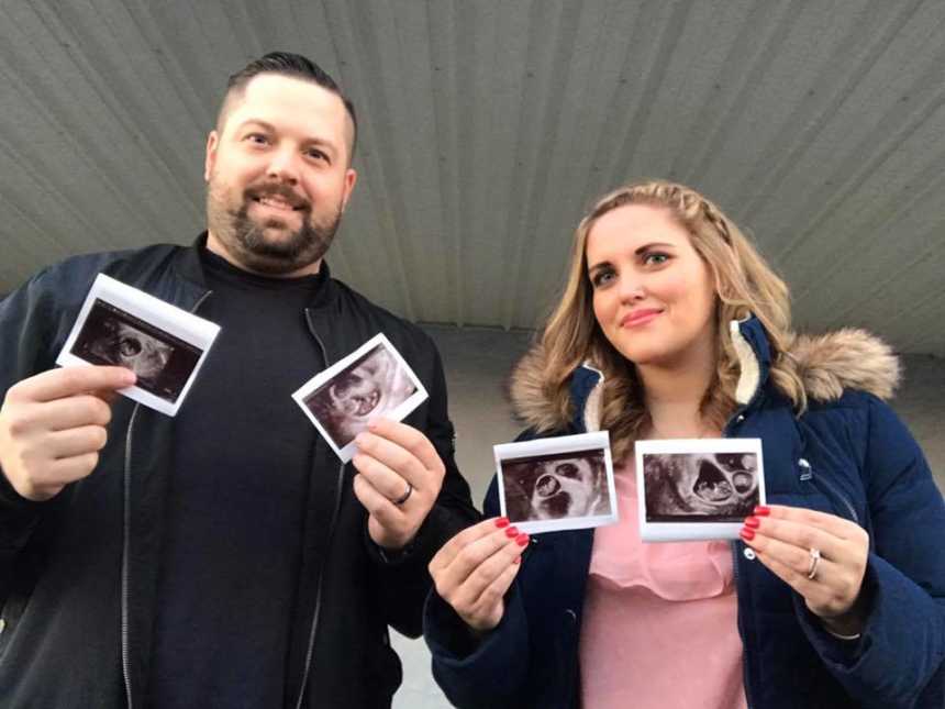 husband and wife smile while holding up sonogram pictures in each of their hands