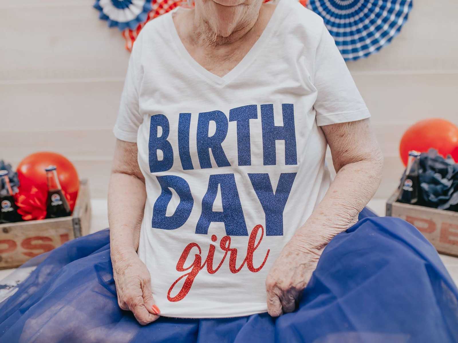 close up of elderly woman holding her t-shirt that reads, "birthday girl"