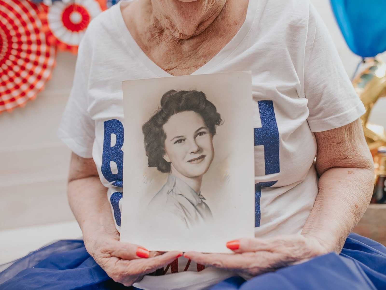 close up of elderly woman holding drawing of her younger self