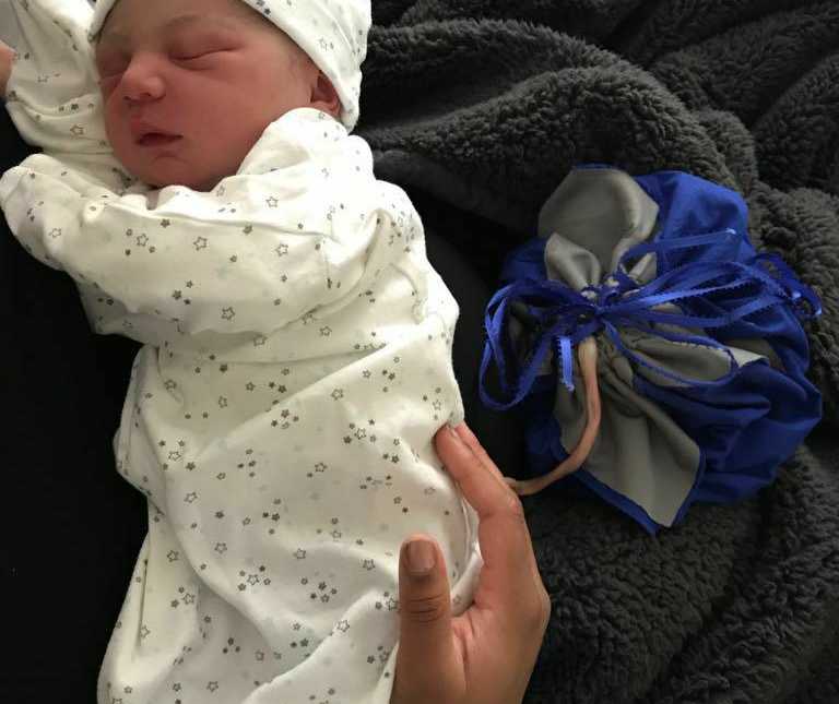 newborn baby sleeping in stars pj and matching hat with placenta attached in blue bag 