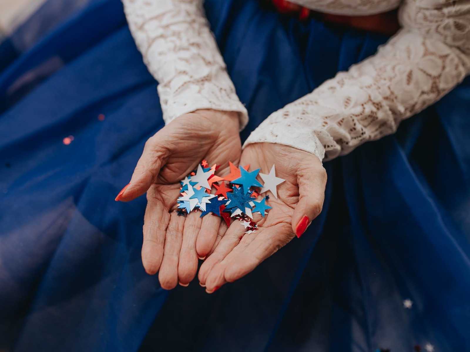 close up of elderly woman's hands holding small red white and blue stars