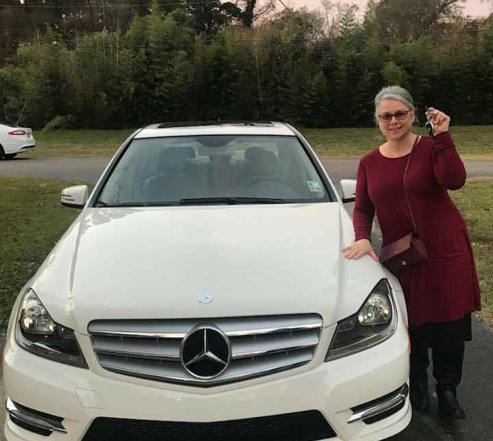 Woman stands holding her keys next to brand new white Mercedes