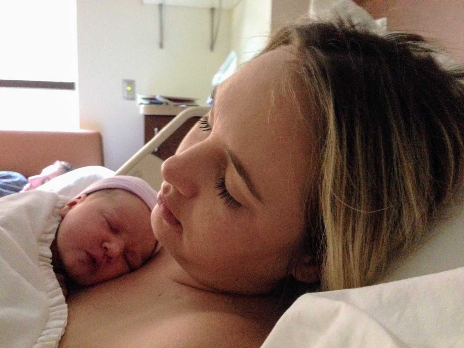 Woman who just gave birth sleeps while holding newborn to chest