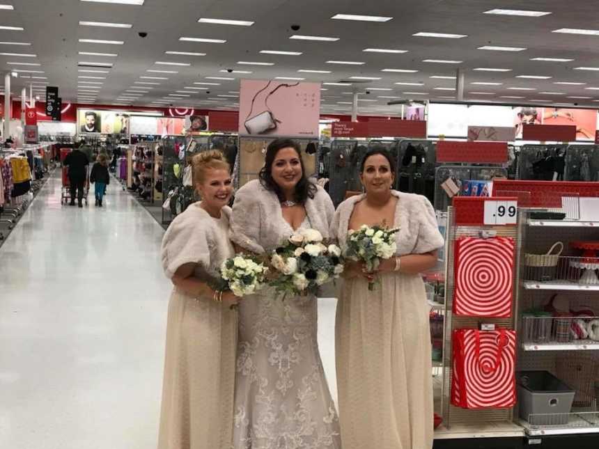 bride has two women in the wedding party standing on either side of her in a target aisle with shoppers in background