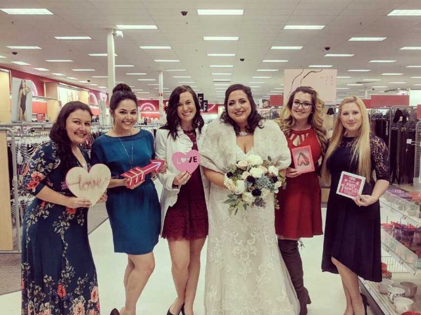 bride smiles with wedding guests on either side of her holding up heart items that are for sale at target 