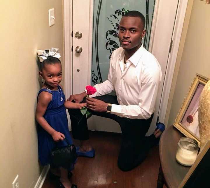 father hands daughter rose while down on one knee in front hallway of home