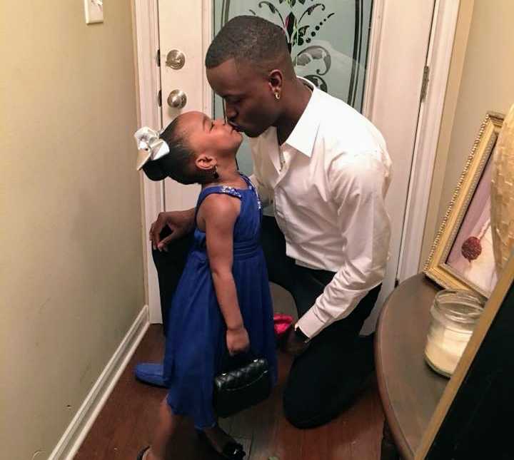 father and daughter share a kiss in front hallway of home
