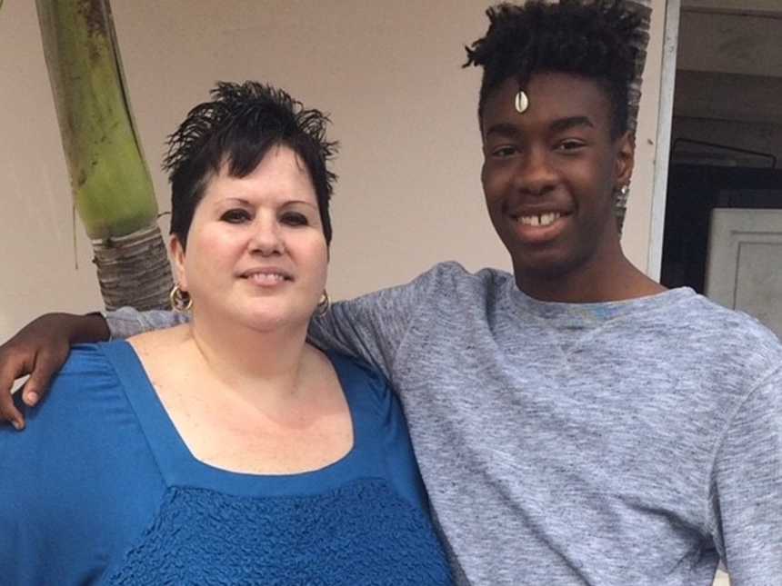 son smiles standing next to his mom with his arm around her