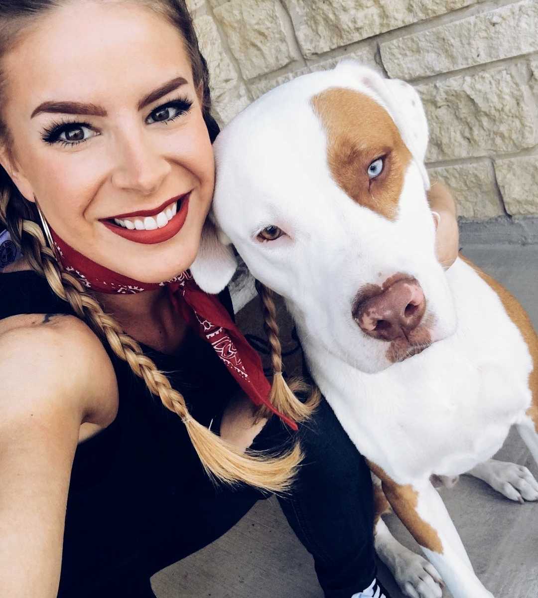 Woman crouches down smiling taking a selfie with dog