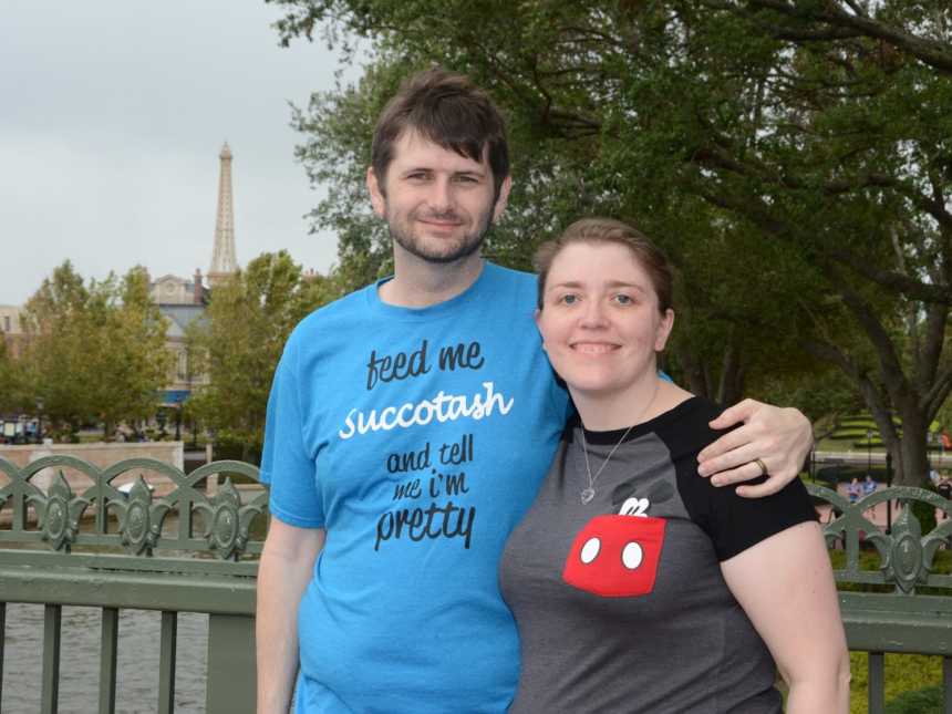 Married couple stand arm and arm at Epcot after combined 160 pound weight loss with Eiffel tower in background 