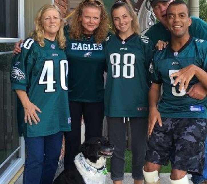 man with cerebral palsy standing with three women and his father who are all wearing philadelphia eagles jerseys