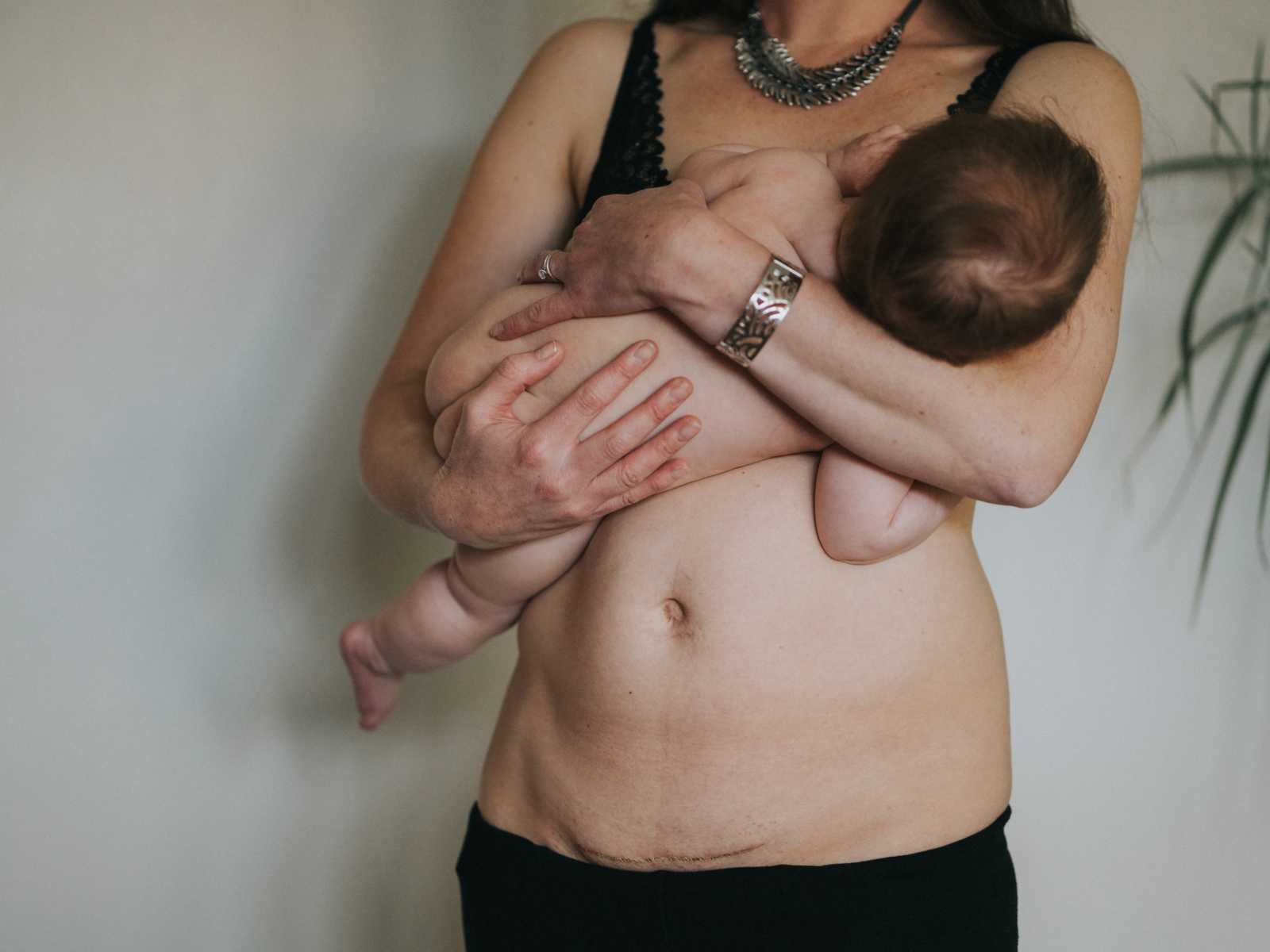 Close up of woman breastfeeding with c-section scar showing covered in gold dust