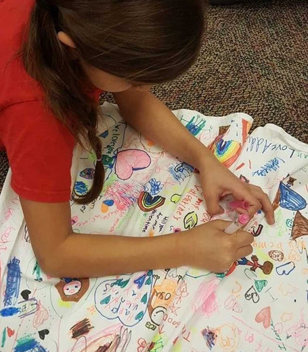 close up of young girl drawing on teachers white dress
