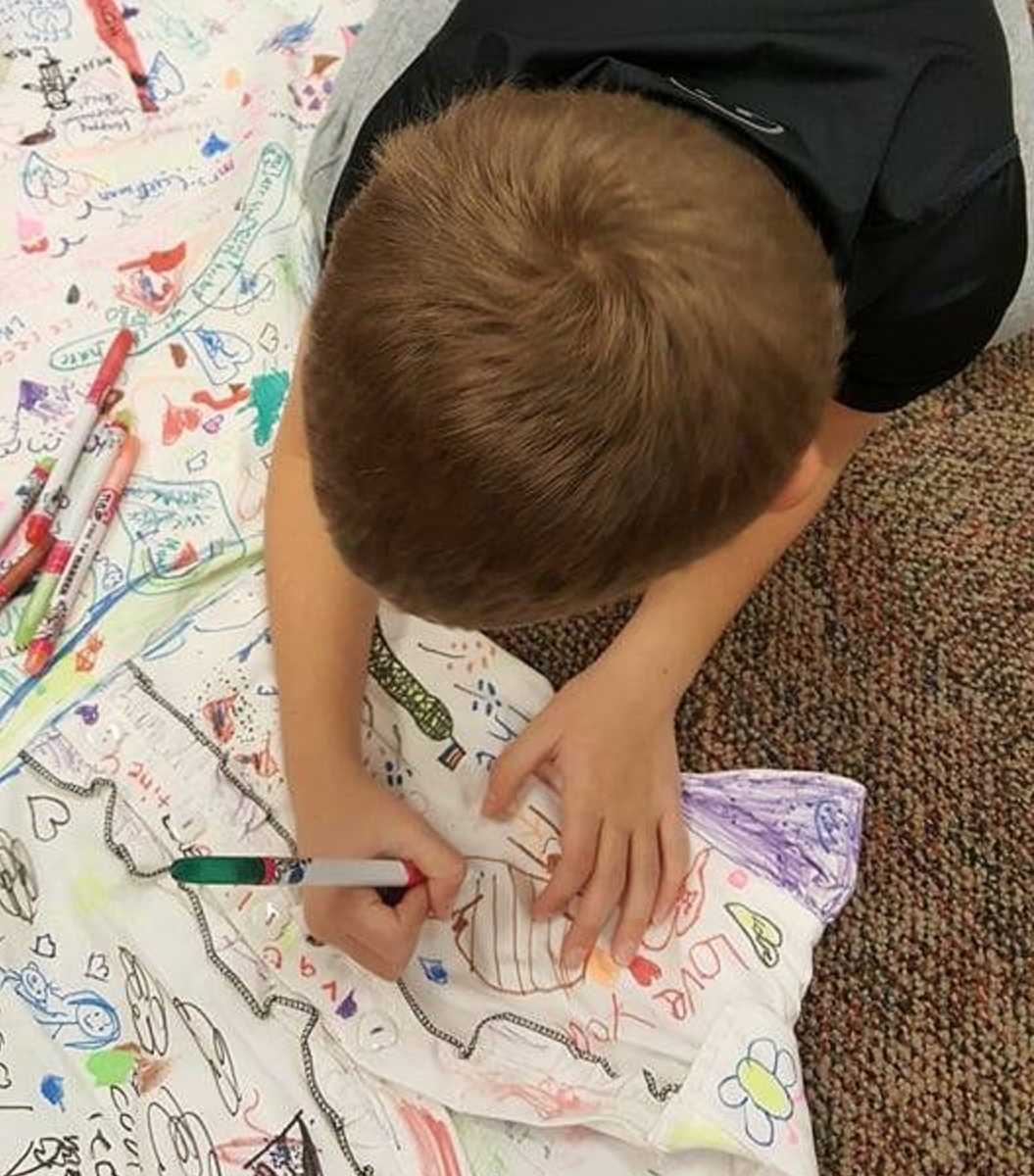 close up of young boy drawing on teachers white dress