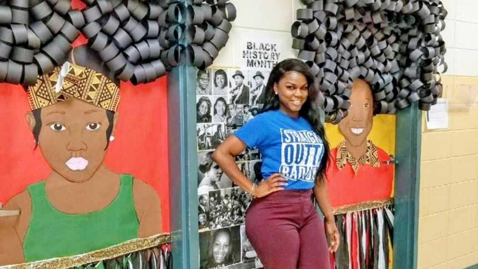 Teacher proudly stands next to her Black History Month artwork