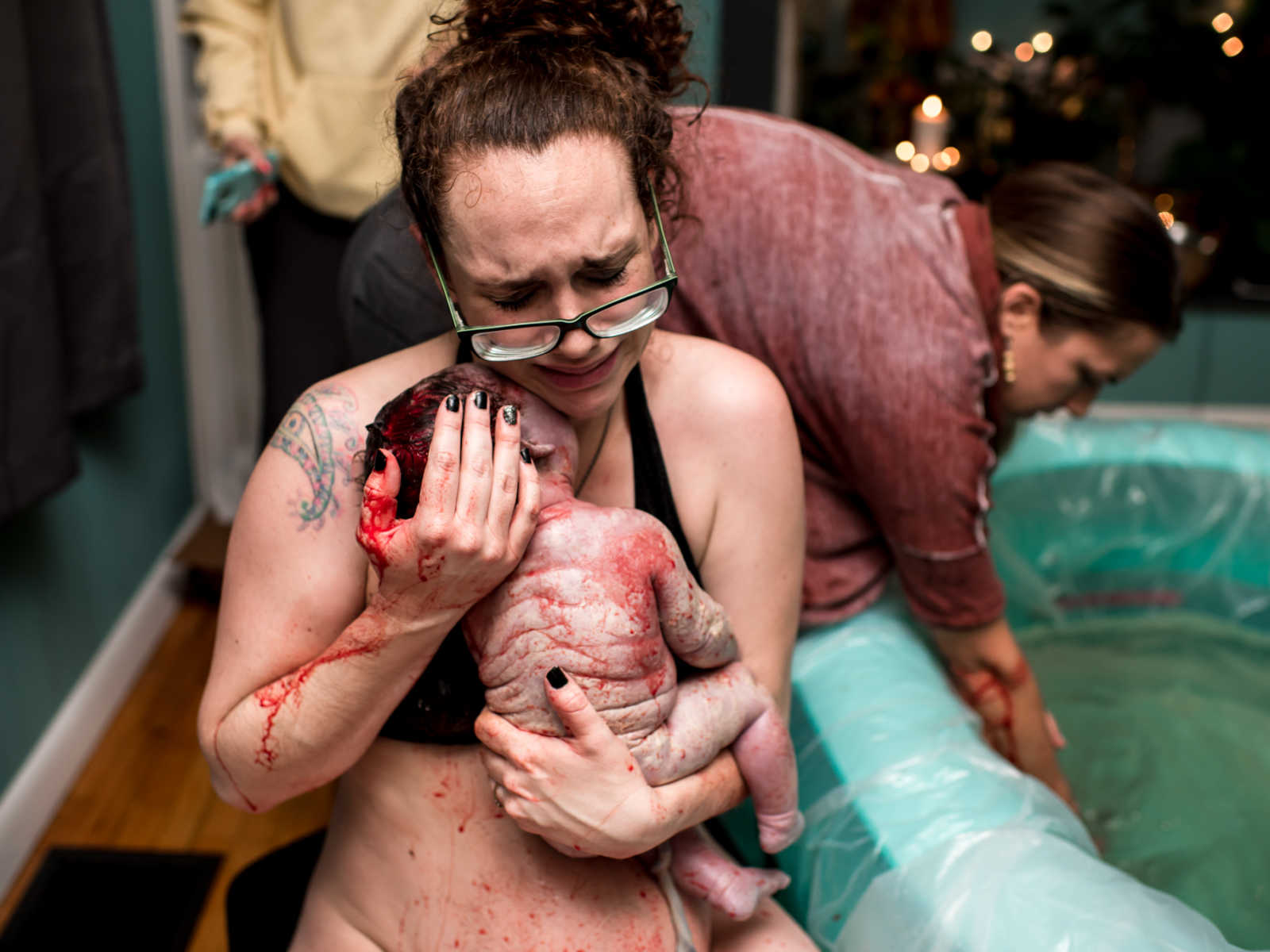 Woman holding 11 pound newborn to chest crying beside birthing pool