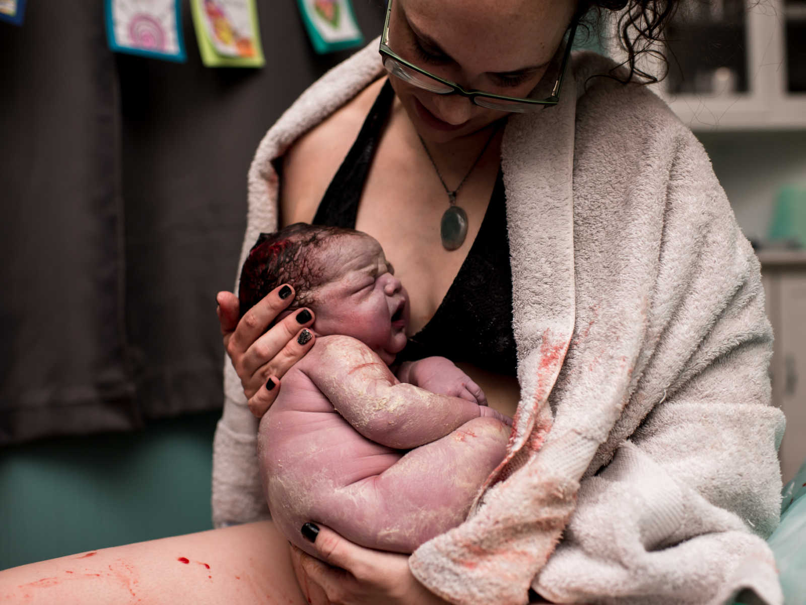 Woman wrapped in towel holding 11 pound newborn in her lap 