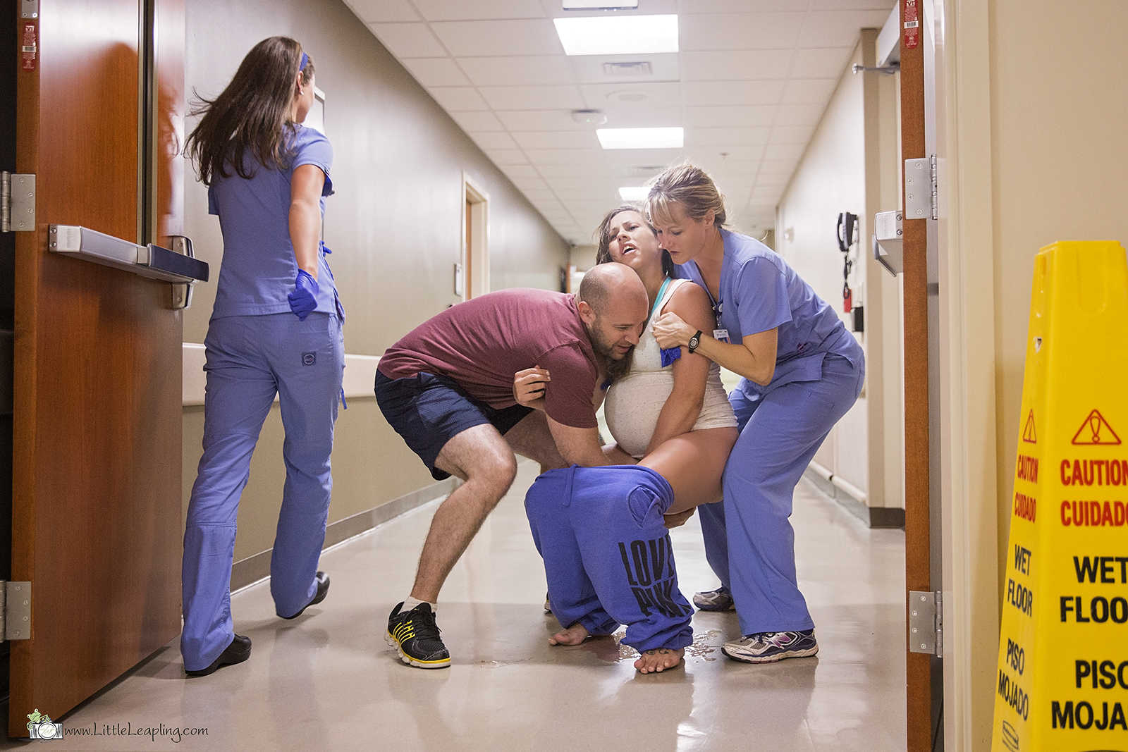 pregnant woman squats down as a nurse holds her up and husband holds his hands under her legs
