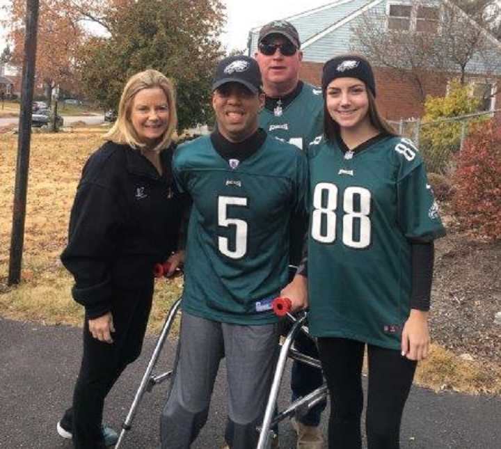 Cerebral Palsy survivor poses with mother father and sister in the driveway with philadelphia eagles apparel on