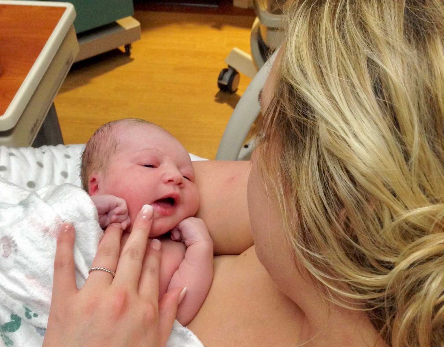 Woman with postpartum thyroid condition looks down at newborn in her arms