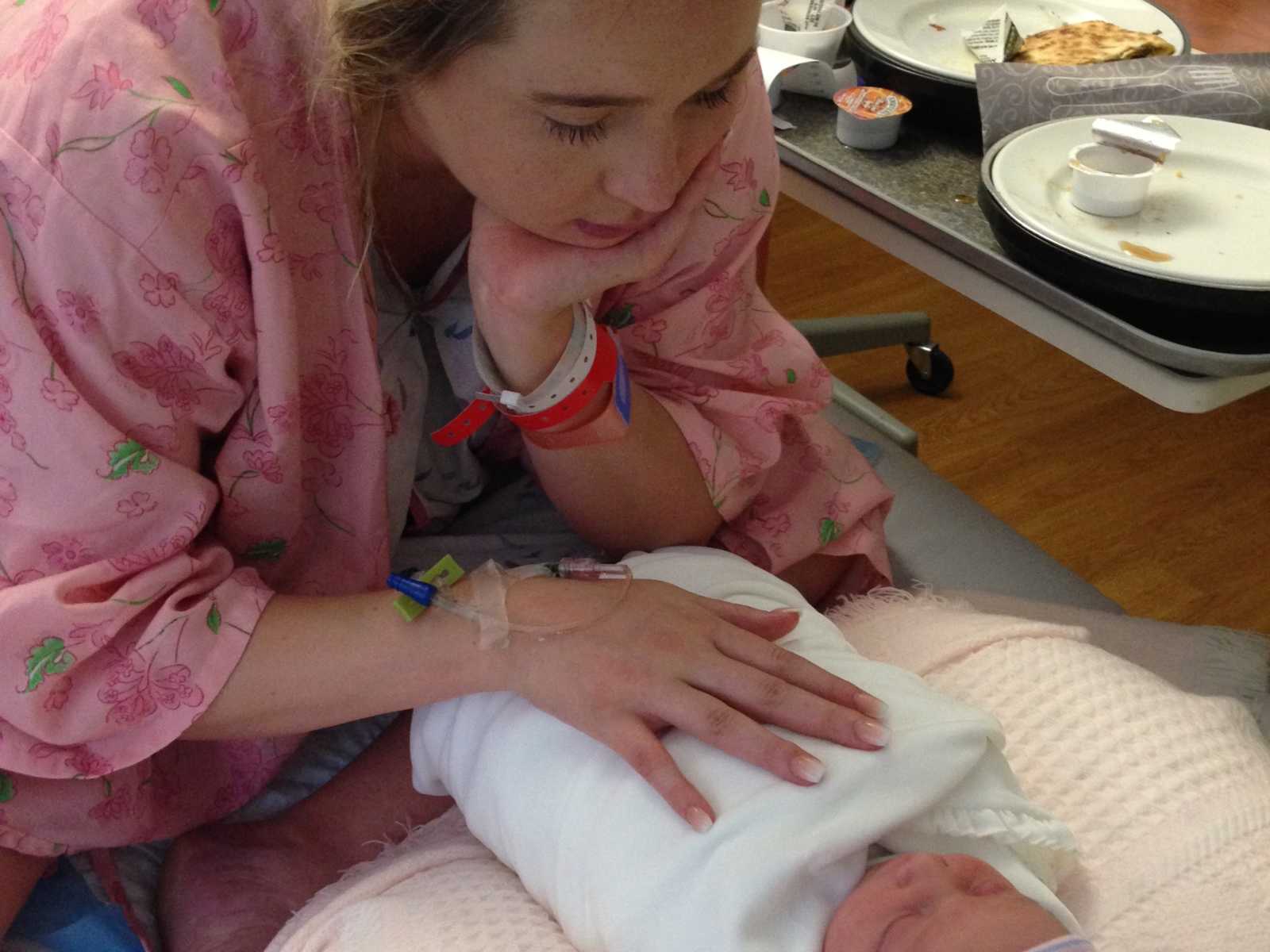 Woman who struggles from postpartum thyroid condition holds chest of newborn swaddled in blanket