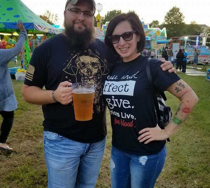 husband holds pitcher of beer while arm is wrapped around wife with cancer at fair