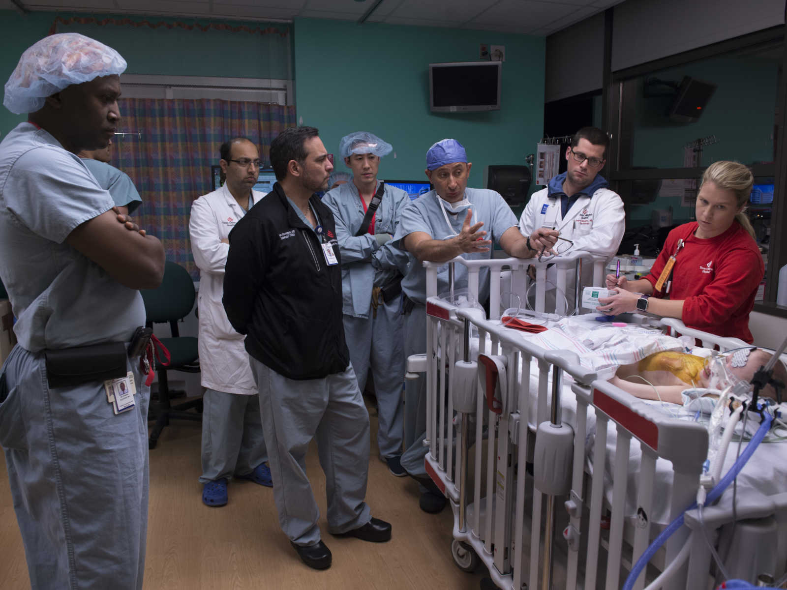 twin post surgery in hospital bed surrounded by doctors looking at her