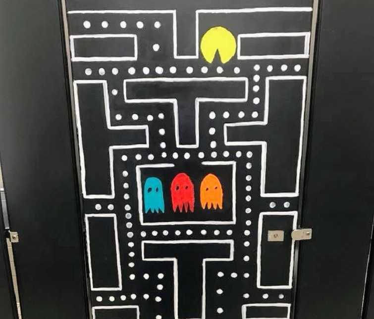 black bathroom stall door with pac-man scene painted on it