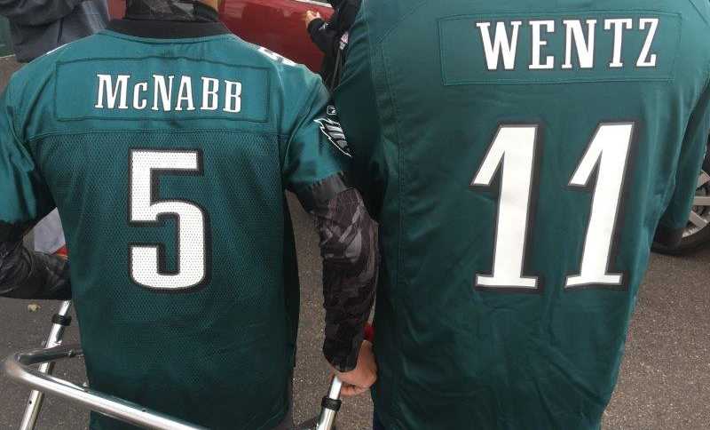 backs of two men wearing Philadelphia eagles jersey, one with number 5 and name McNabb and other number 11 with name Wentz