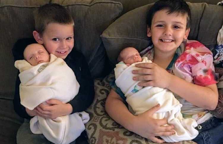 Older brothers of twins who need bone marrow transplant hold smile while holding them on the couch