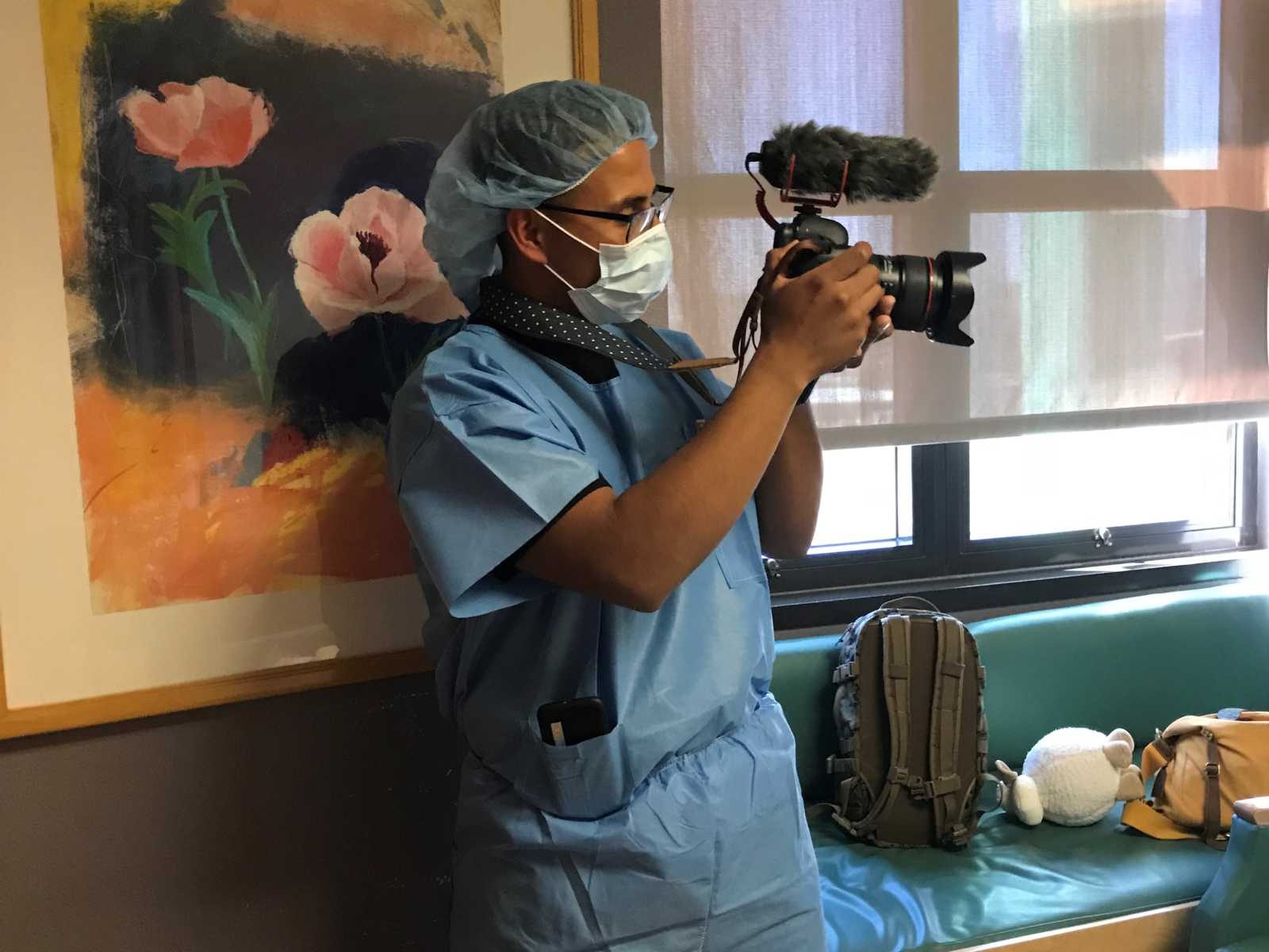 Marine stands in hospital room holding up a camera 