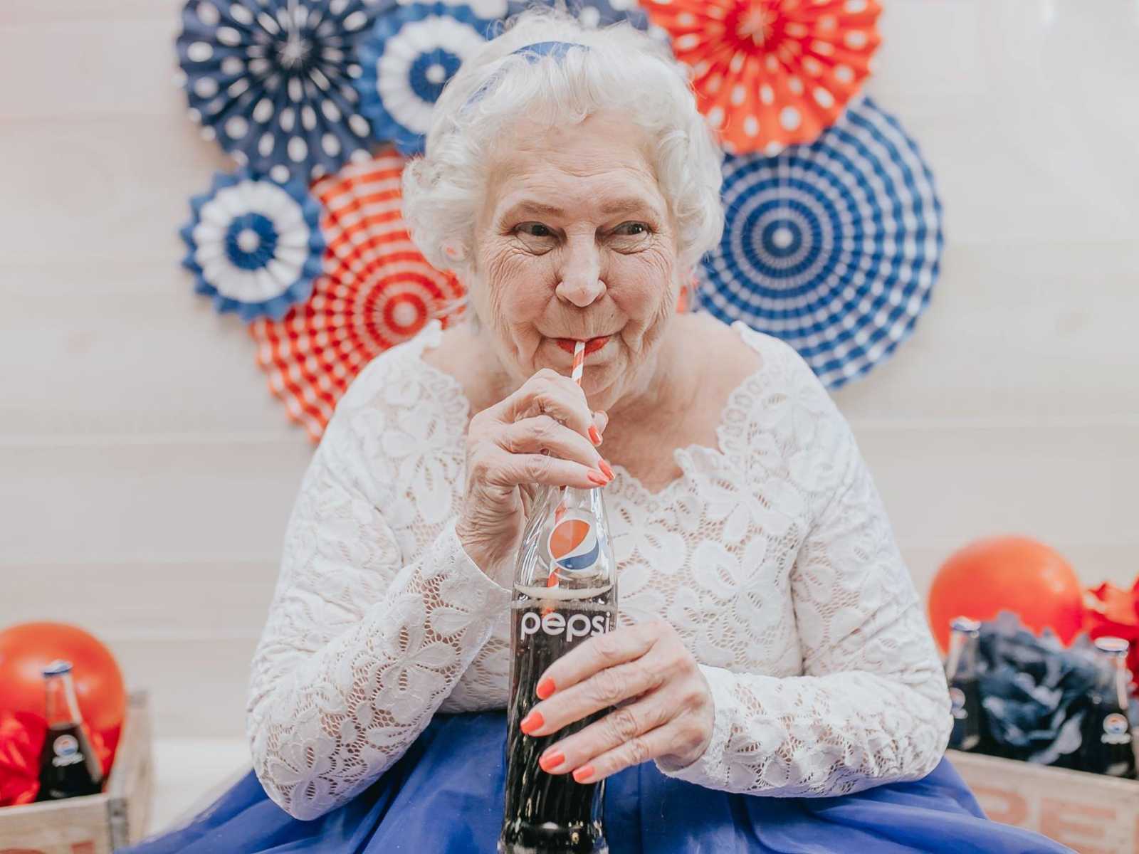 close up of elderly woman sipping pepsi out of a red and white striped straw