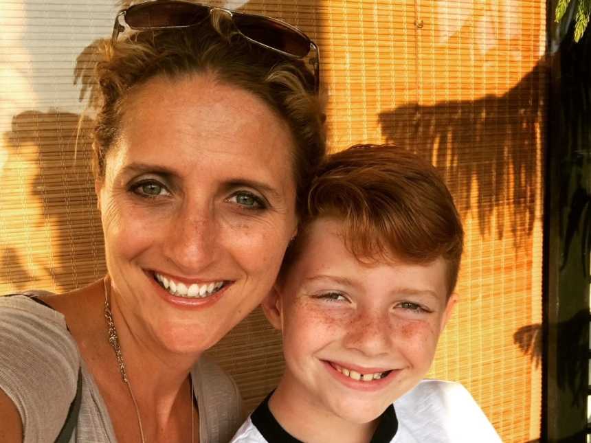 mother with sunglasses on head smiles next to red haired son in selfie