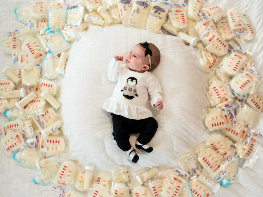 Newborn baby surrounded by donated breast milk