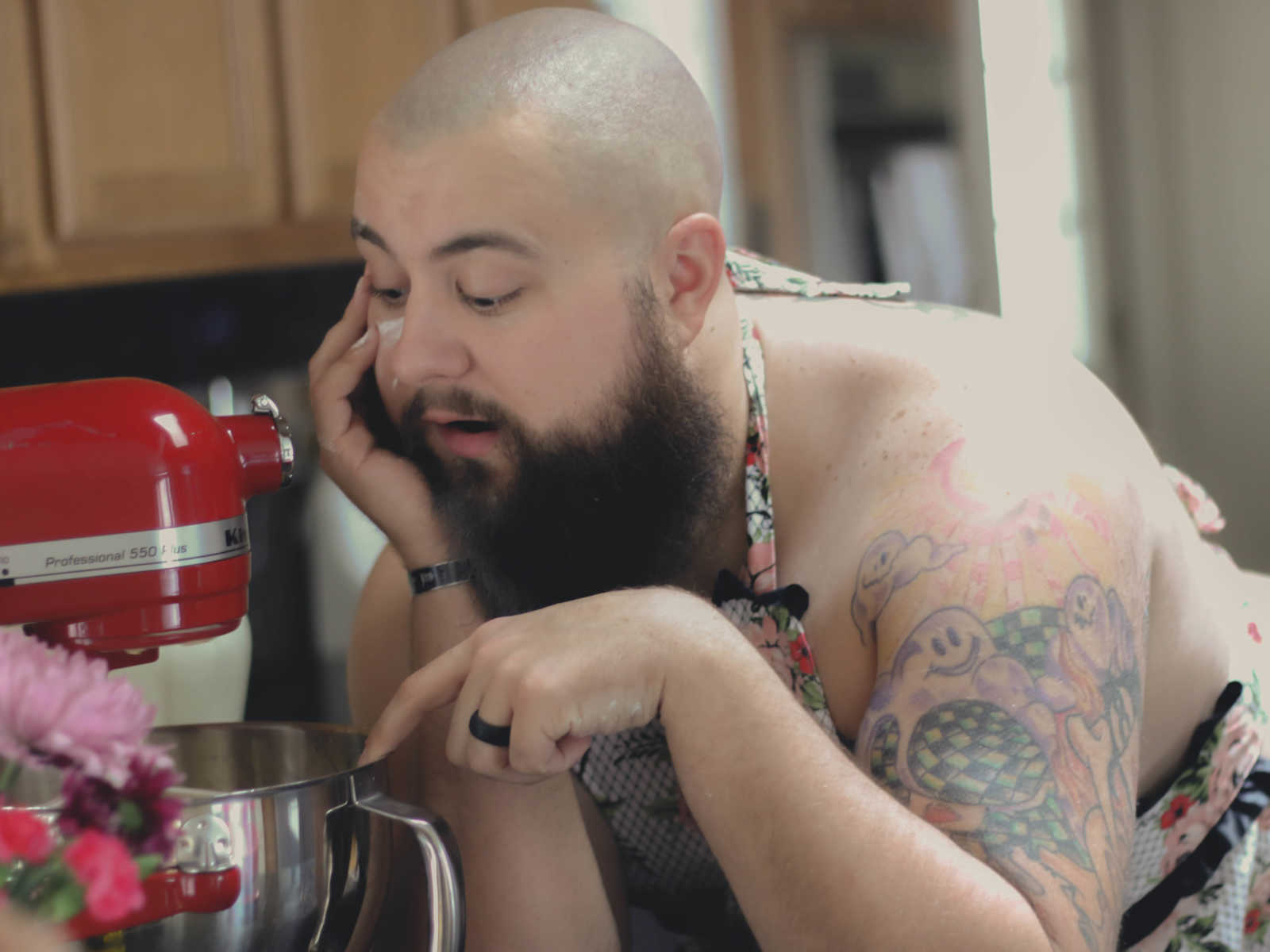 close up of man resting cheek on hand looking into kitchen aid mixer