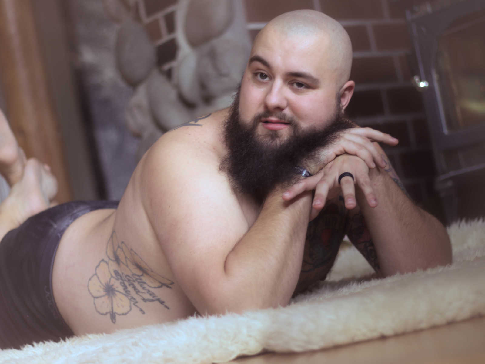 husband poses on stomach on fur rug with head resting on hands