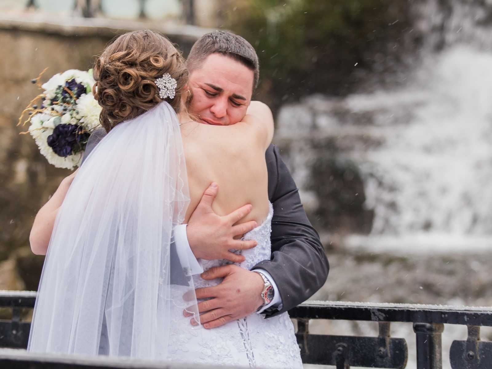 bride and groom embrace while groom cries