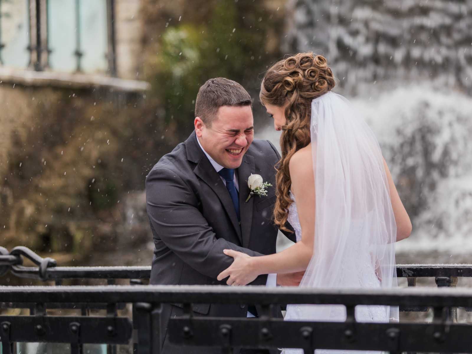 bride and groom holding each other while laughing