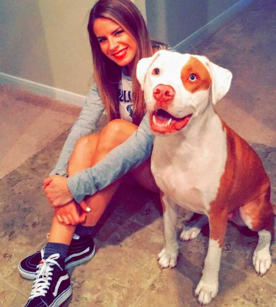 woman sits next to smiling dog