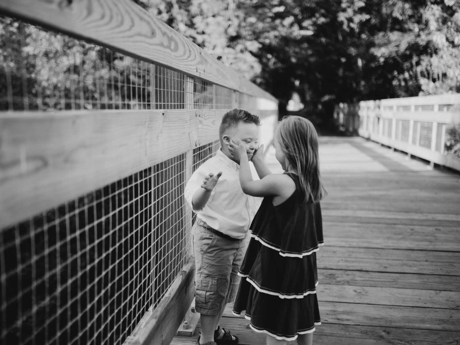 Down syndrome girl holding cheeks of down syndrome boy