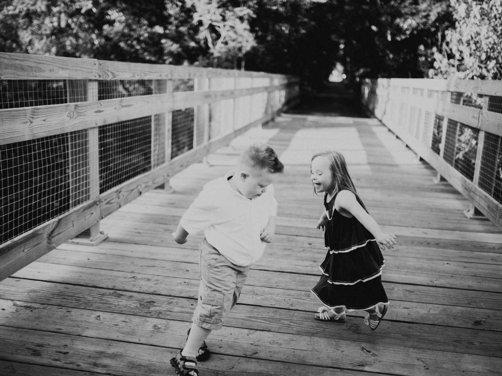 Down syndrome girl laughing at down syndrome boy on bridge