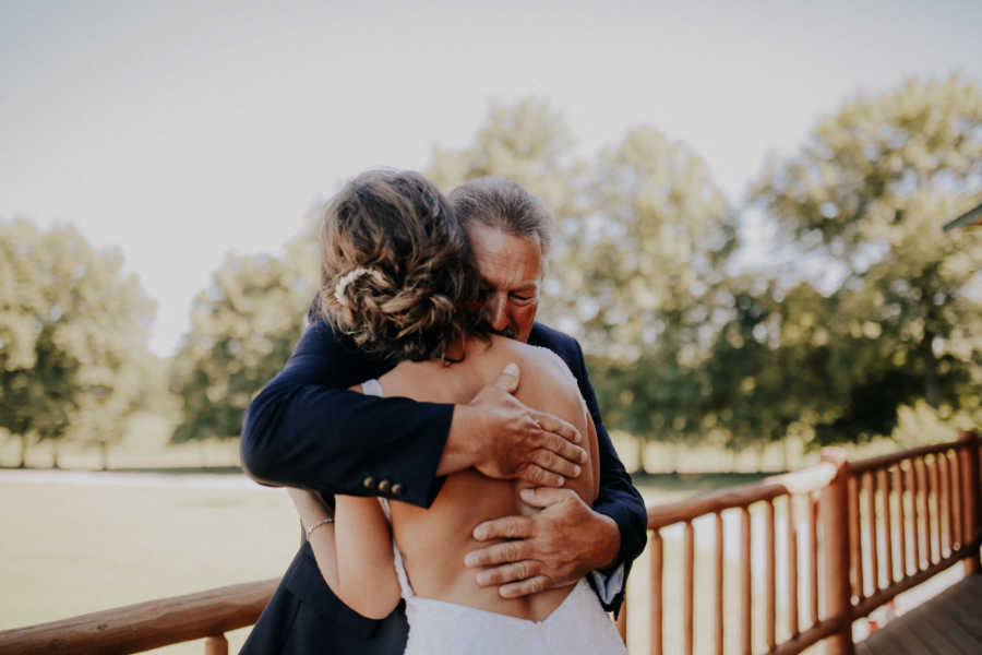 Daughter and bride hugs farmer father