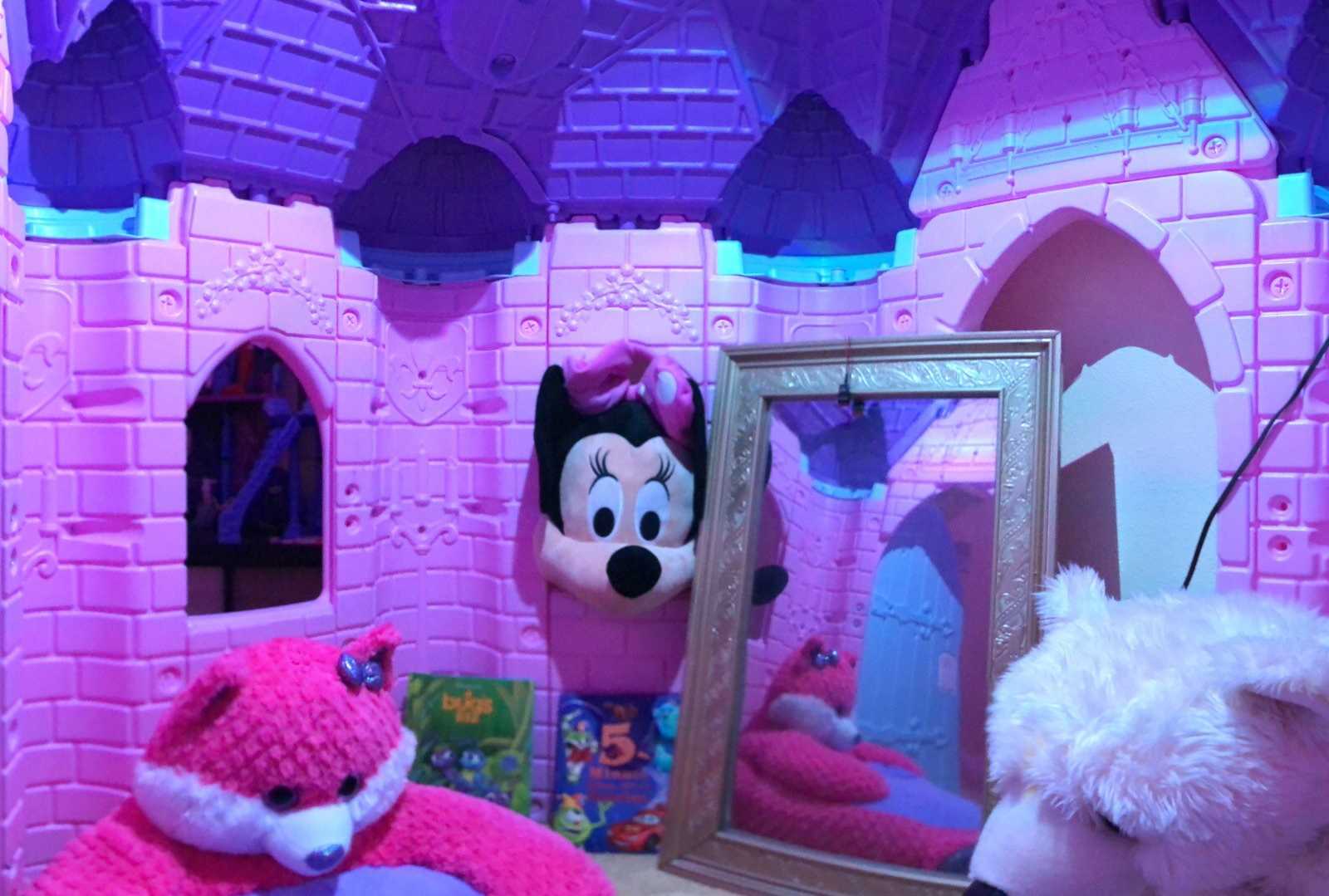 Inside of little girl's castle with stuffed animals and Minnie Mouse, books, and mirror